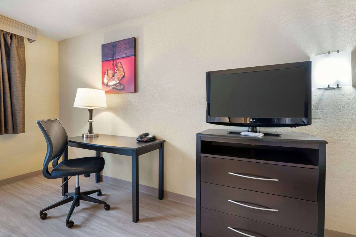 Une chambre d’hôtel équipée d’un bureau, d’une chaise, d’une télévision et d’une lampe.