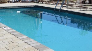 Una piscina con borde de ladrillo y escalera de metal.