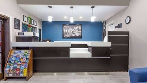 A reception area with a blue wall, a framed artwork, a clock, and a display rack with brochures. - Super 8 by Wyndham Bakersfield South CA (Bakersfield)