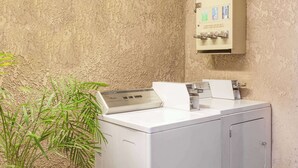 A laundry area with a washing machine and a detergent dispenser on a textured wall. - Super 8 by Wyndham Bakersfield South CA (Bakersfield)