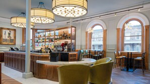 A bar area with wooden furniture, a counter, and a large window. - The Queen at Chester Hotel - Handwritten Collection (Chester)