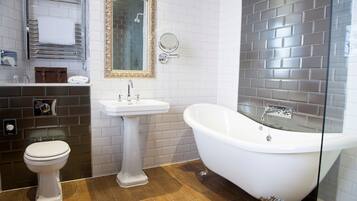 A bathroom with a white toilet, pedestal sink, and freestanding bathtub.