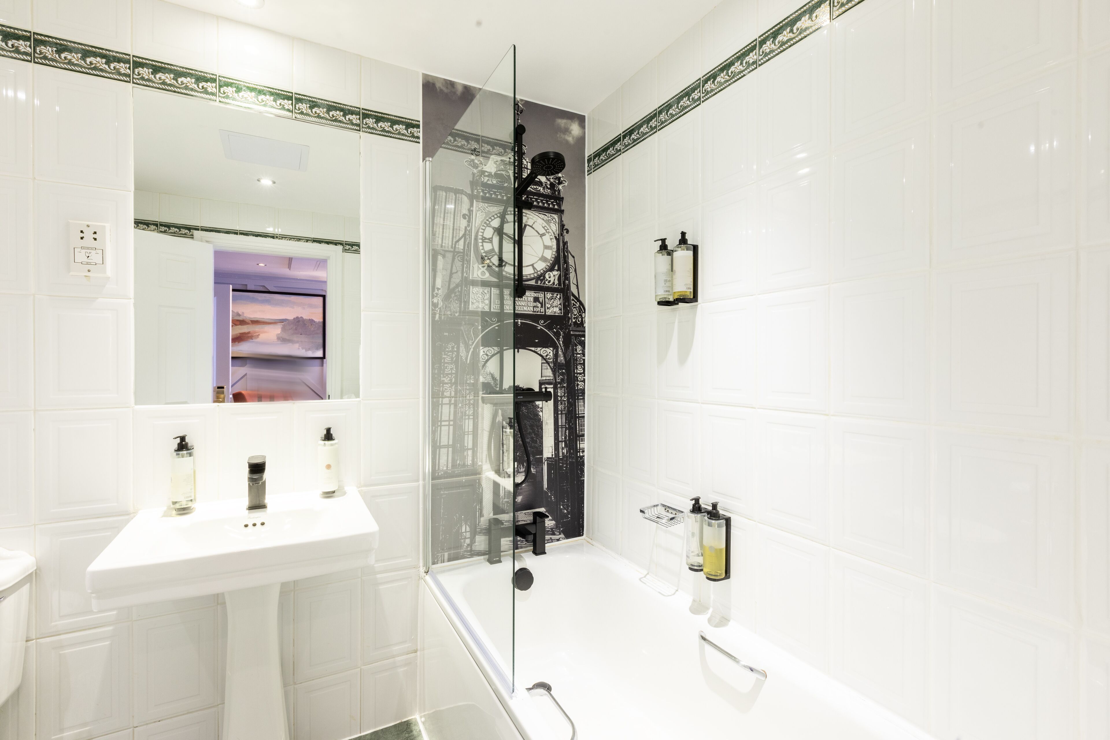 A modern bathroom with a white sink, a glass shower enclosure, and a large mirror.
