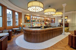A bar area with wooden furniture, a round bar counter, and hanging lamps. - The Queen at Chester Hotel - Handwritten Collection (Chester)
