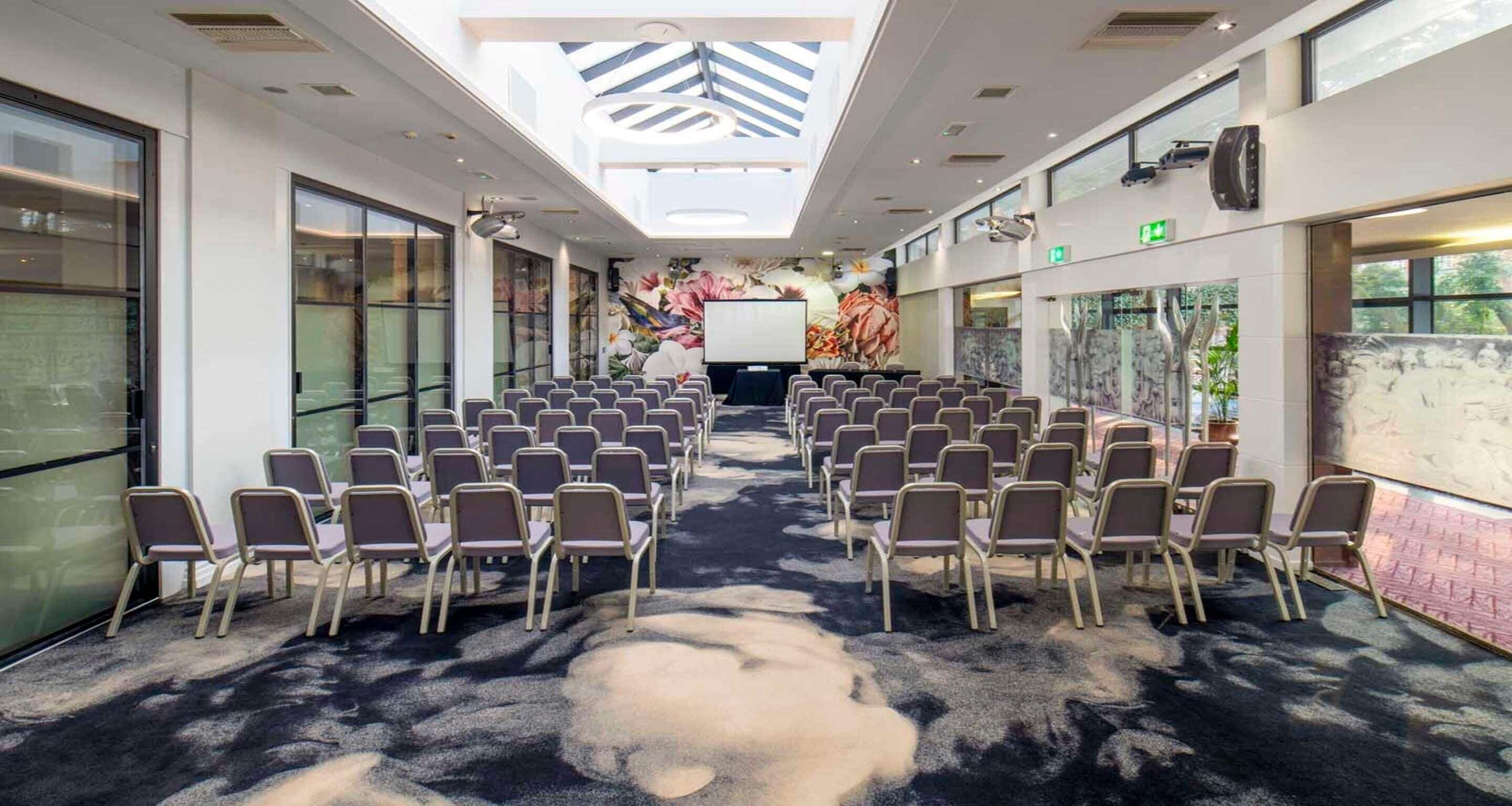 Una sala conferenze con file di sedie, una lavagna e un'ampia finestra.