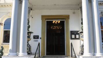 The entrance to the Queen Hotel with a classic facade, a grand staircase, and a sign for Kings' Grill.