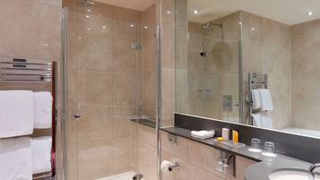 A modern bathroom with a glass-enclosed shower, a vanity with a sink, and a large mirror.