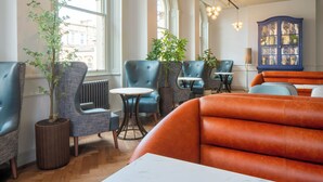 A modern interior with leather sofas, blue armchairs, and a blue cabinet with glass doors. - The Queen at Chester Hotel - Handwritten Collection (Chester)