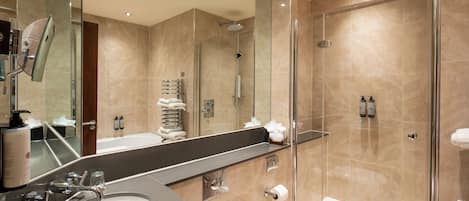 A modern bathroom with a large mirror, a sink, a shower, and a toilet.