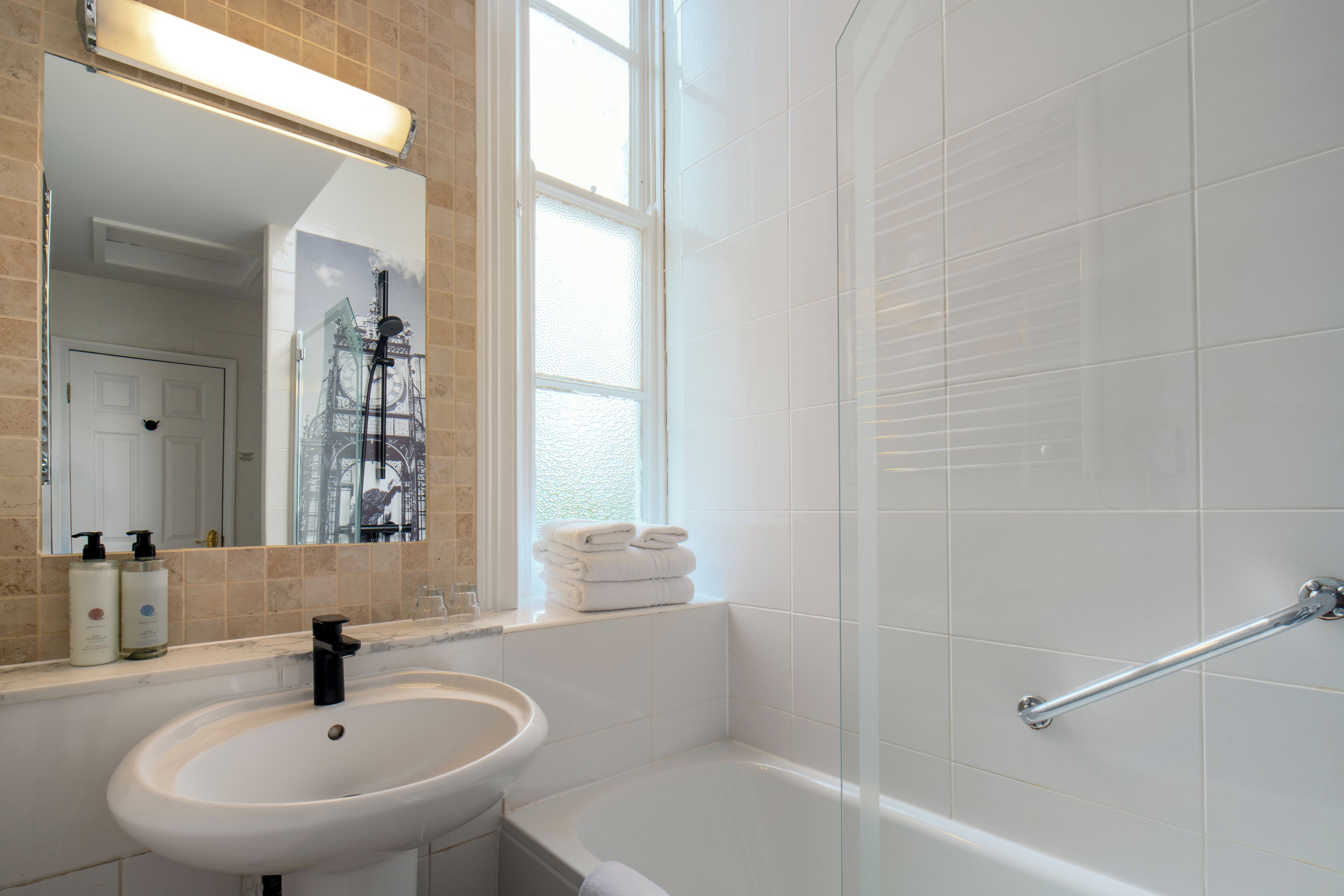 Un baño con lavabo, espejo y cabina de ducha de cristal.