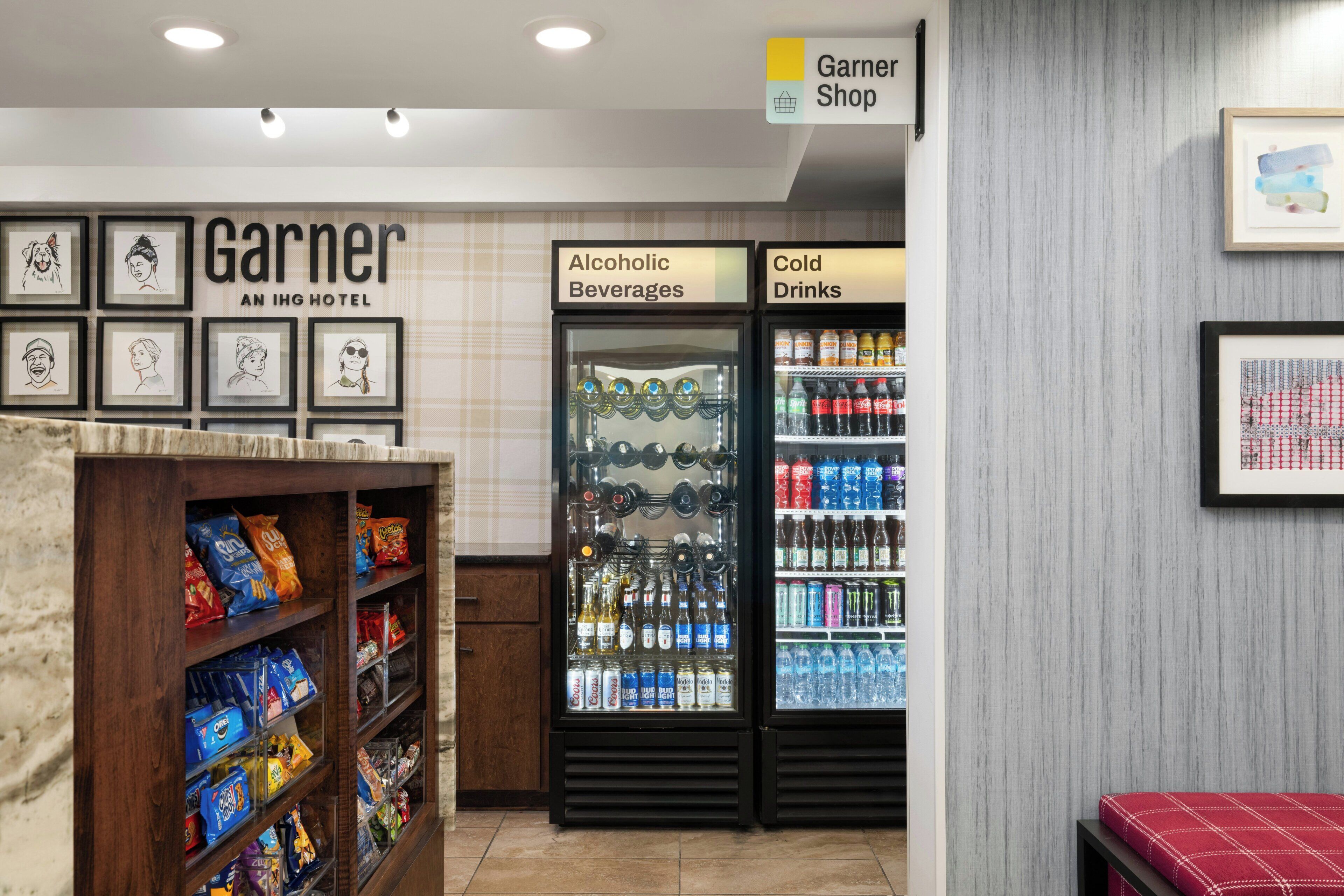 Eine Hotelhalle mit einer Snackbar, einem 'Garner Shop'-Schild und Getränkekühlschränken mit der Aufschrift 'Alkoholische Getränke' und 'Kaltgetränke'.