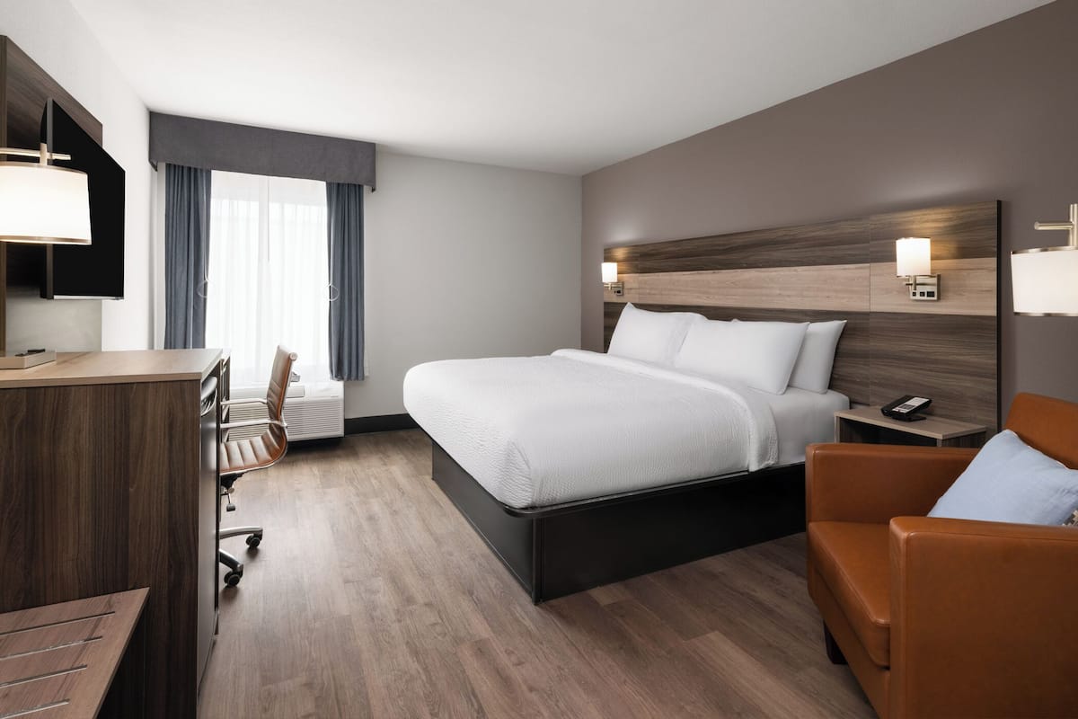 Una habitación de hotel con una cama, un escritorio, una silla y un sofá.