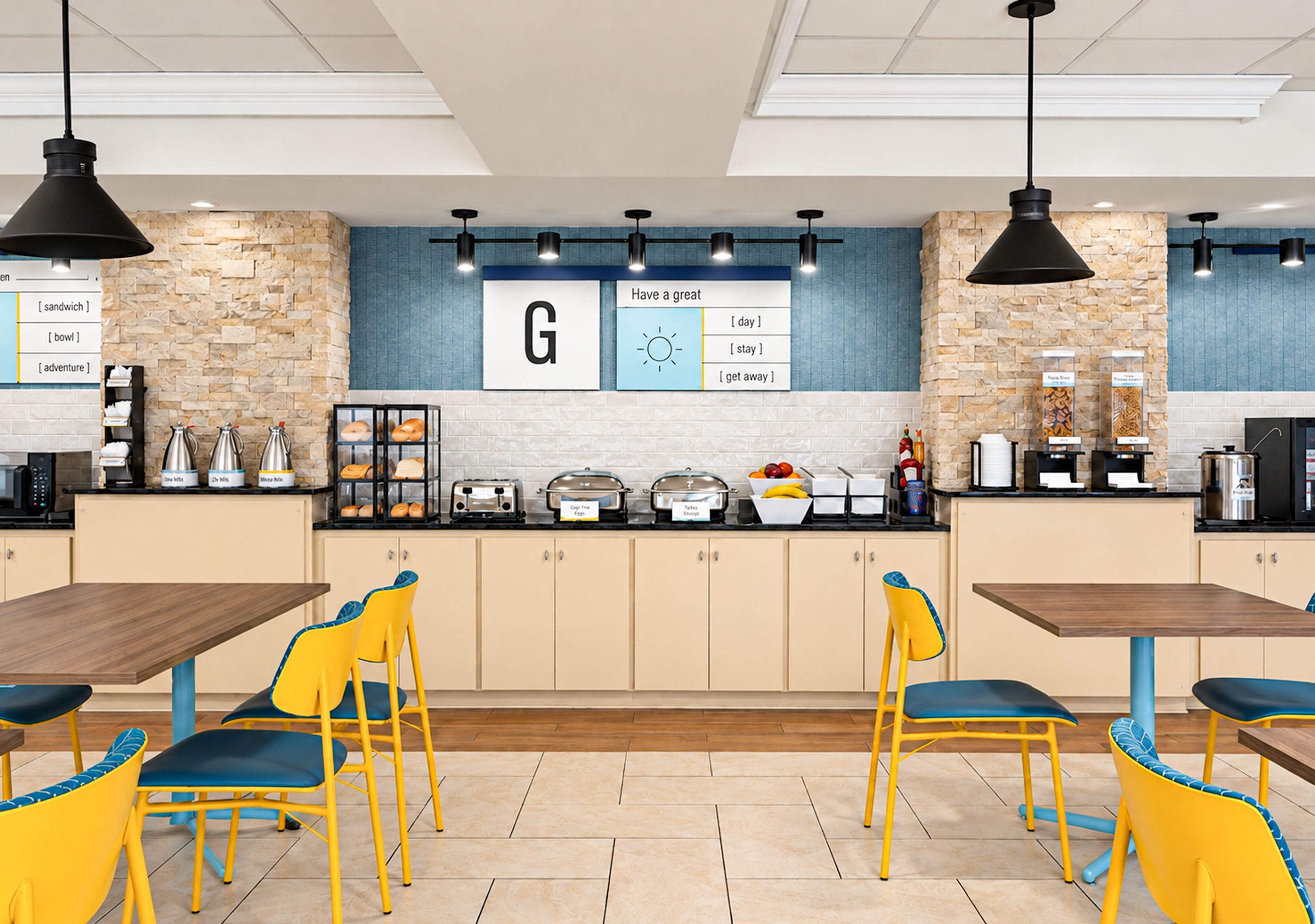 Une cuisine moderne avec des murs en pierre, un îlot central et des chaises jaunes.