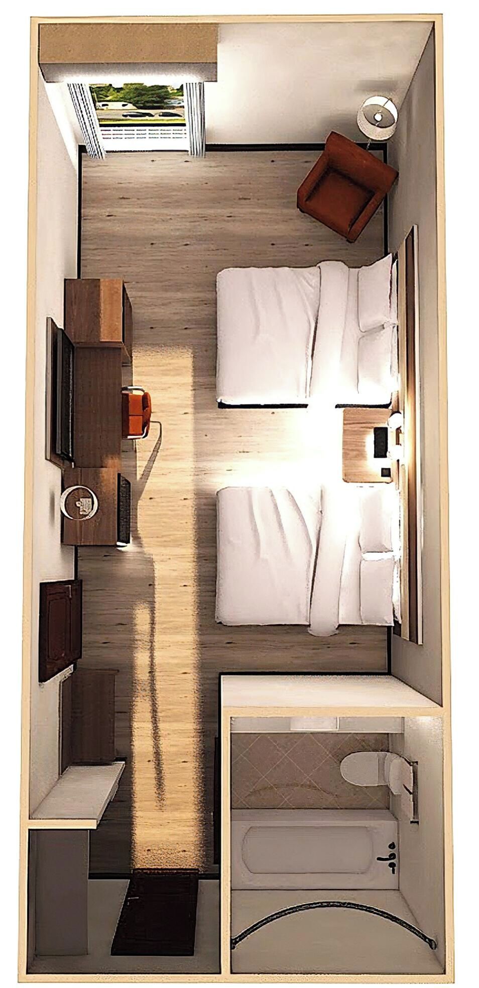 A compact hotel room with a bed, bedside table, lamp, and a small seating area.