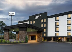 Un hotel de diseño moderno, con un llamativo letrero que dice 'Garner IHG Hotel' y un área de entrada cubierta.