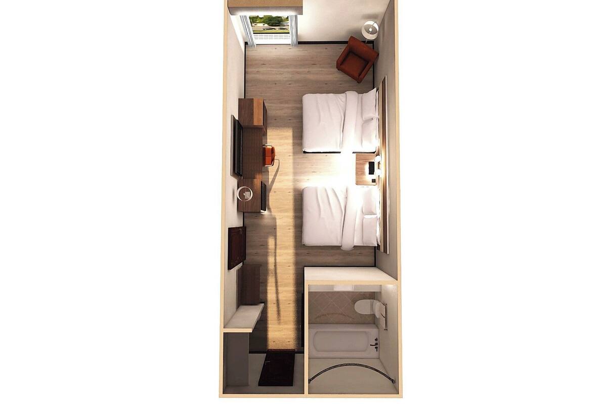 Habitación pequeña con cama, una mesita, una silla, televisión, ventana y baño.
