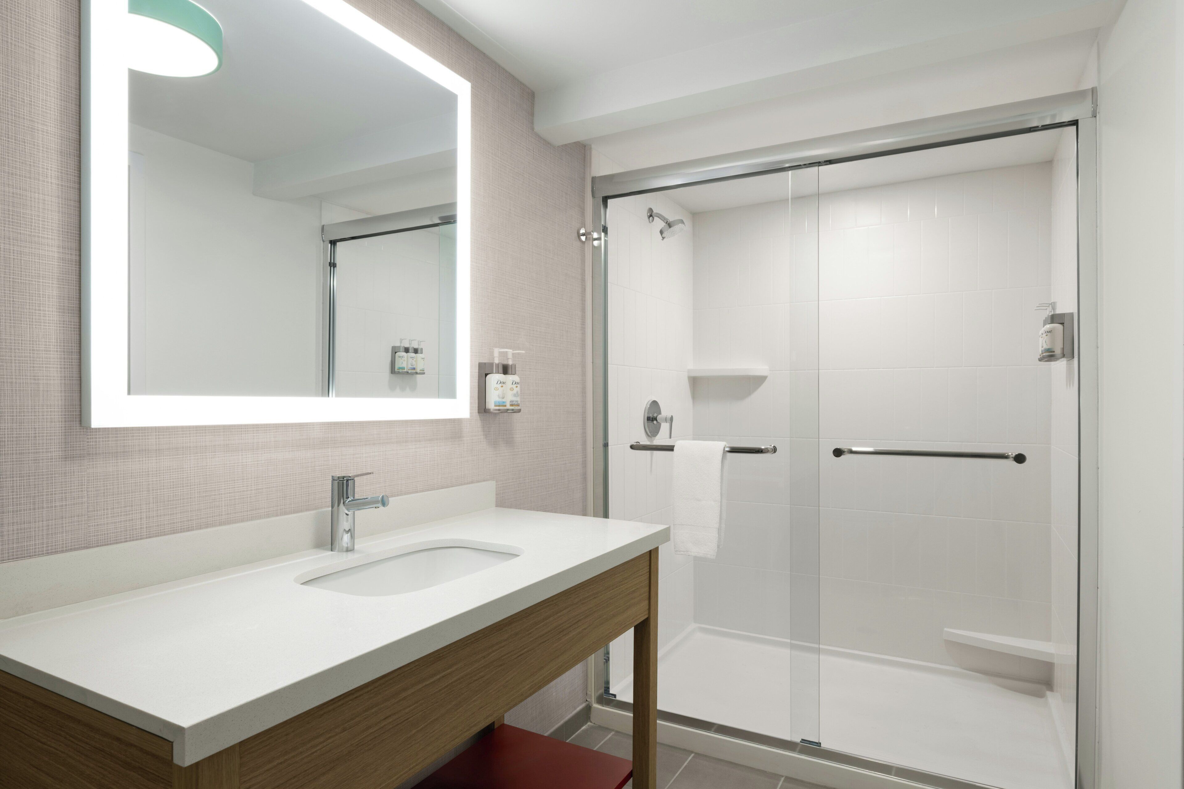 A modern bathroom with a large mirror, a sink, and a shower area.