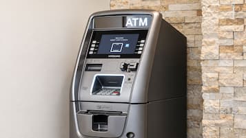 An ATM machine with a digital screen, card slot, cash withdrawal slot, and a keypad.