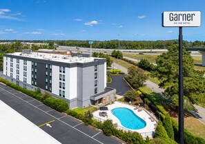 Ein Hotel mit Pool auf dem Dach, Parkplatz und einem Schild mit dem Namen 'Garnier An IHG Hotel'.