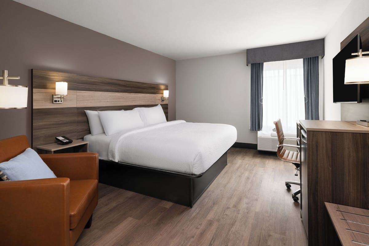 Una habitación de hotel con una cama, un escritorio, una silla, un sofá y un televisor.