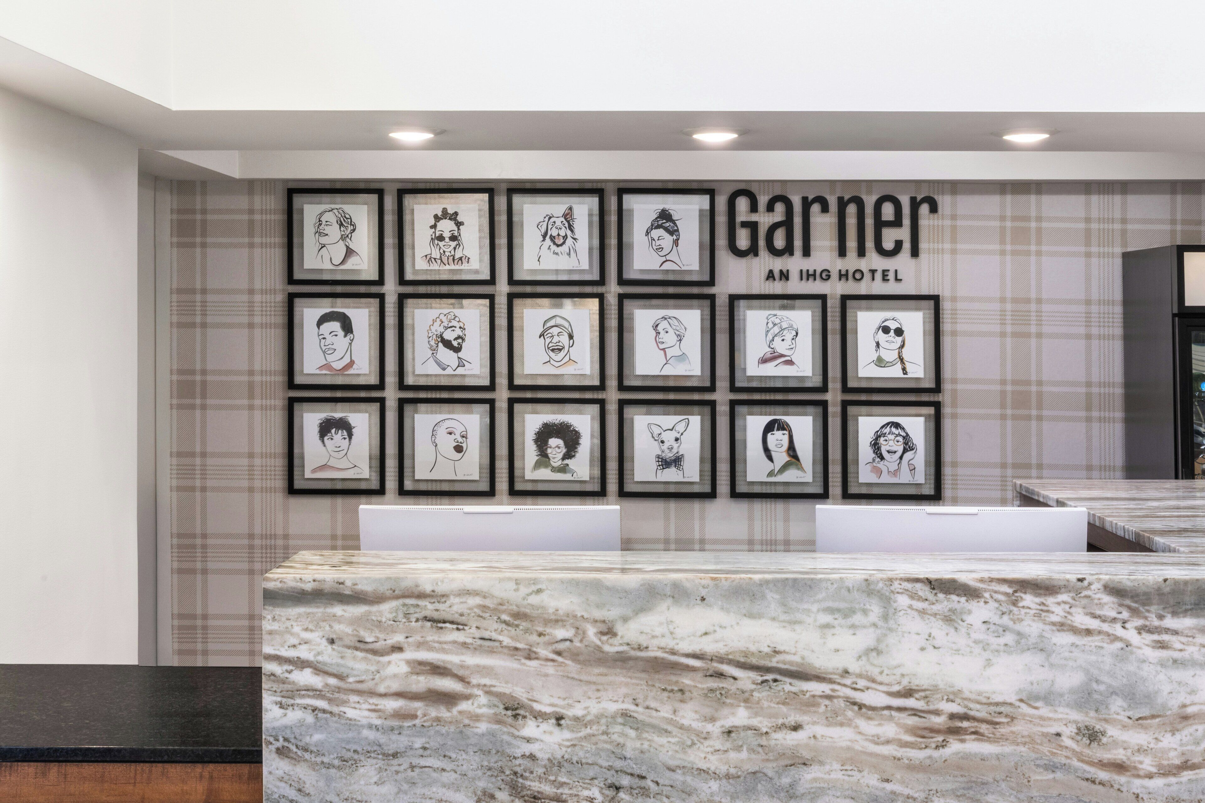 Zona de recepción de un hotel con mostrador de mármol y obras de arte enmarcadas en la pared.