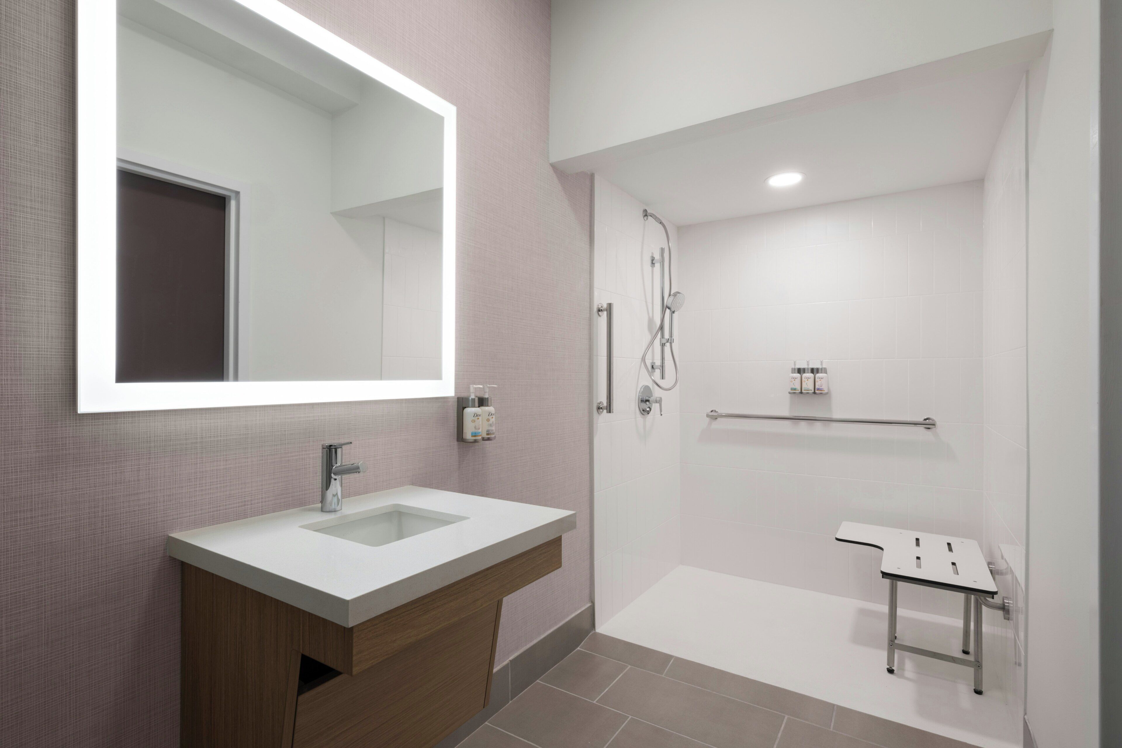 A modern bathroom with a large mirror, a sink, and a shower area.