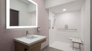 A modern bathroom with a large mirror, a sink, and a shower area.