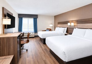 A hotel room with two beds, a desk, a chair, a TV, and a window with curtains. - Garner Hotel August West by IHG (Augusta)