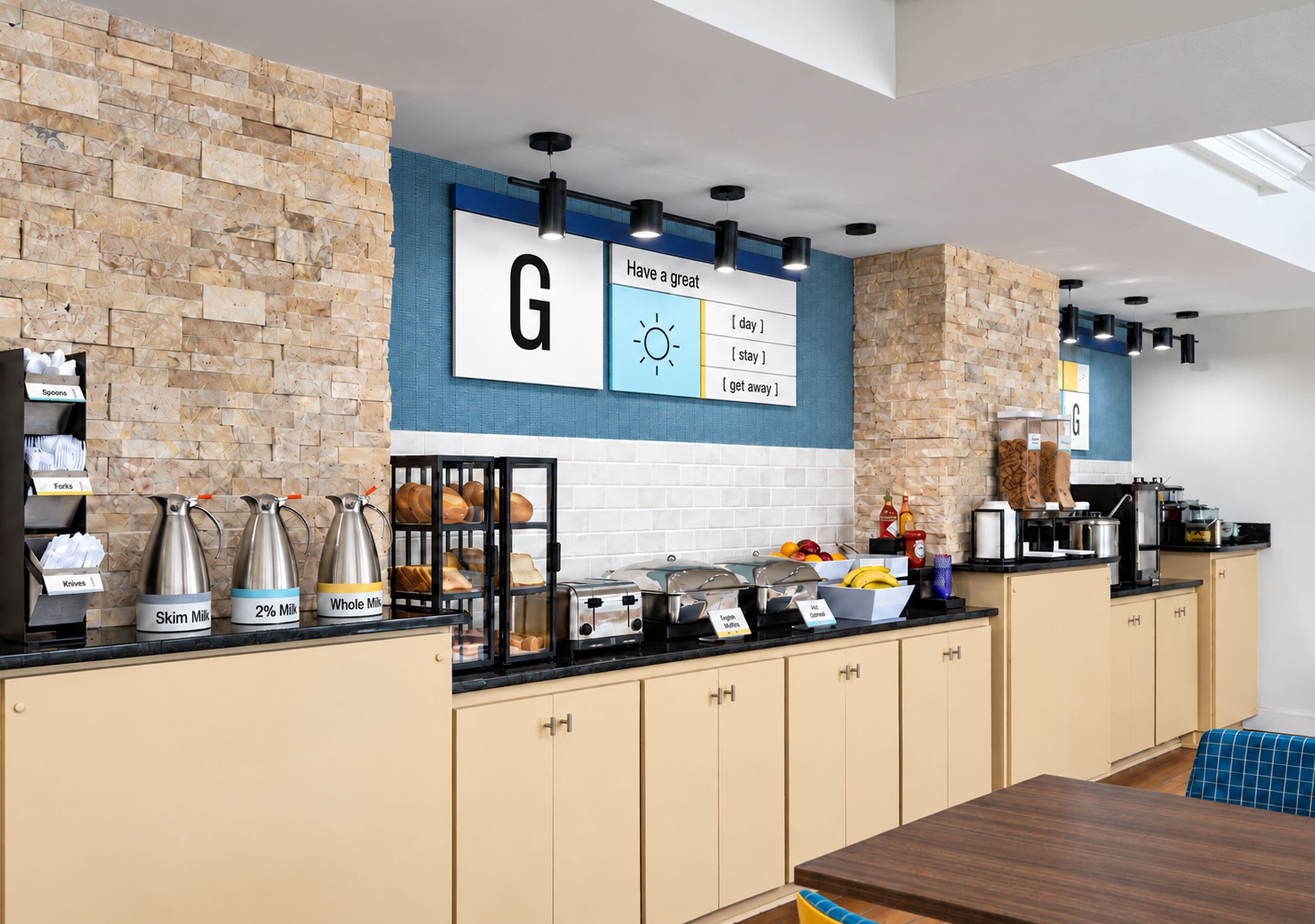 A modern kitchen with a stone wall, a large 'G' sign, and various kitchen appliances.
