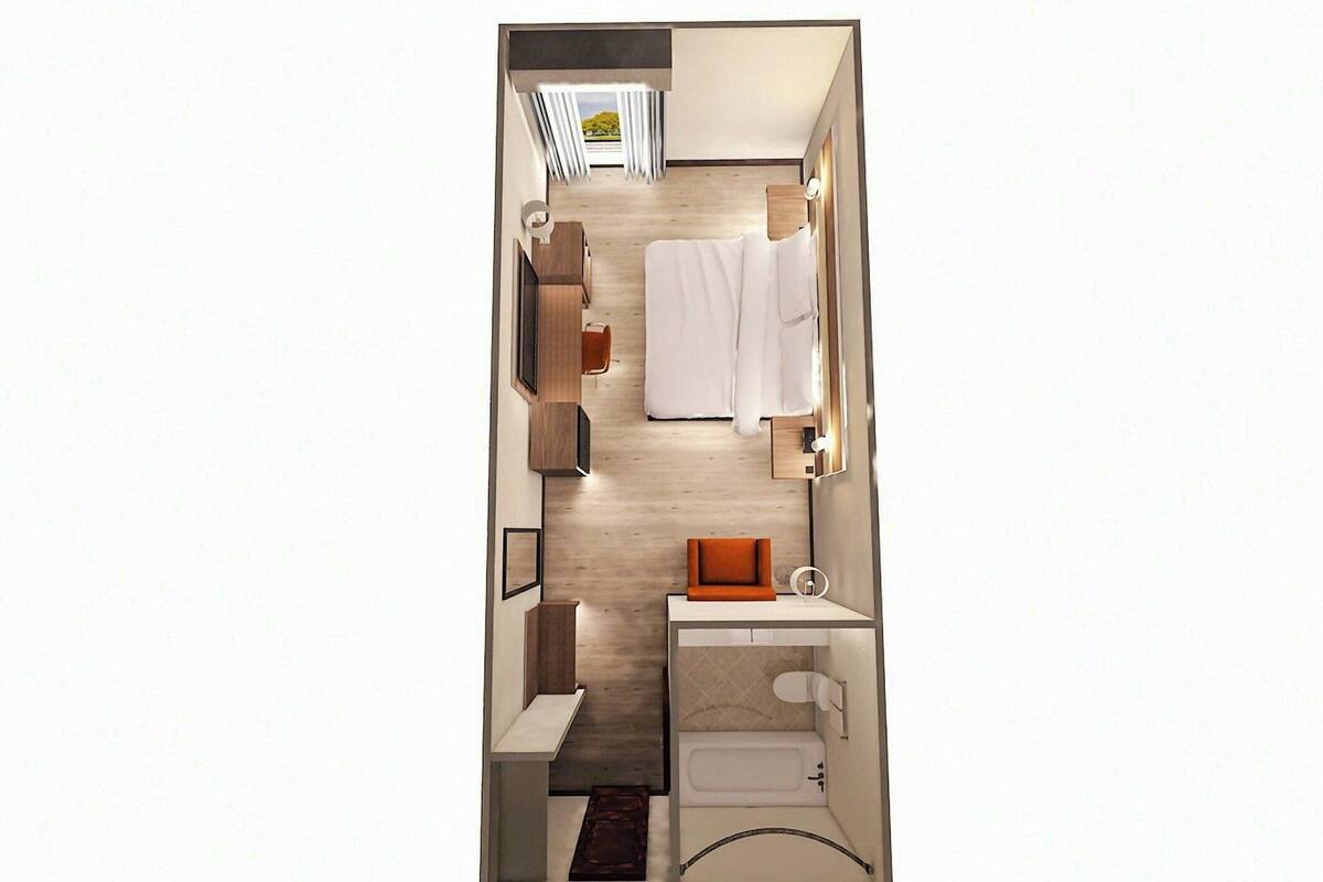 Habitación pequeña con cama, un rincón de descanso, tocador, inodoro y ventana con cortinas.