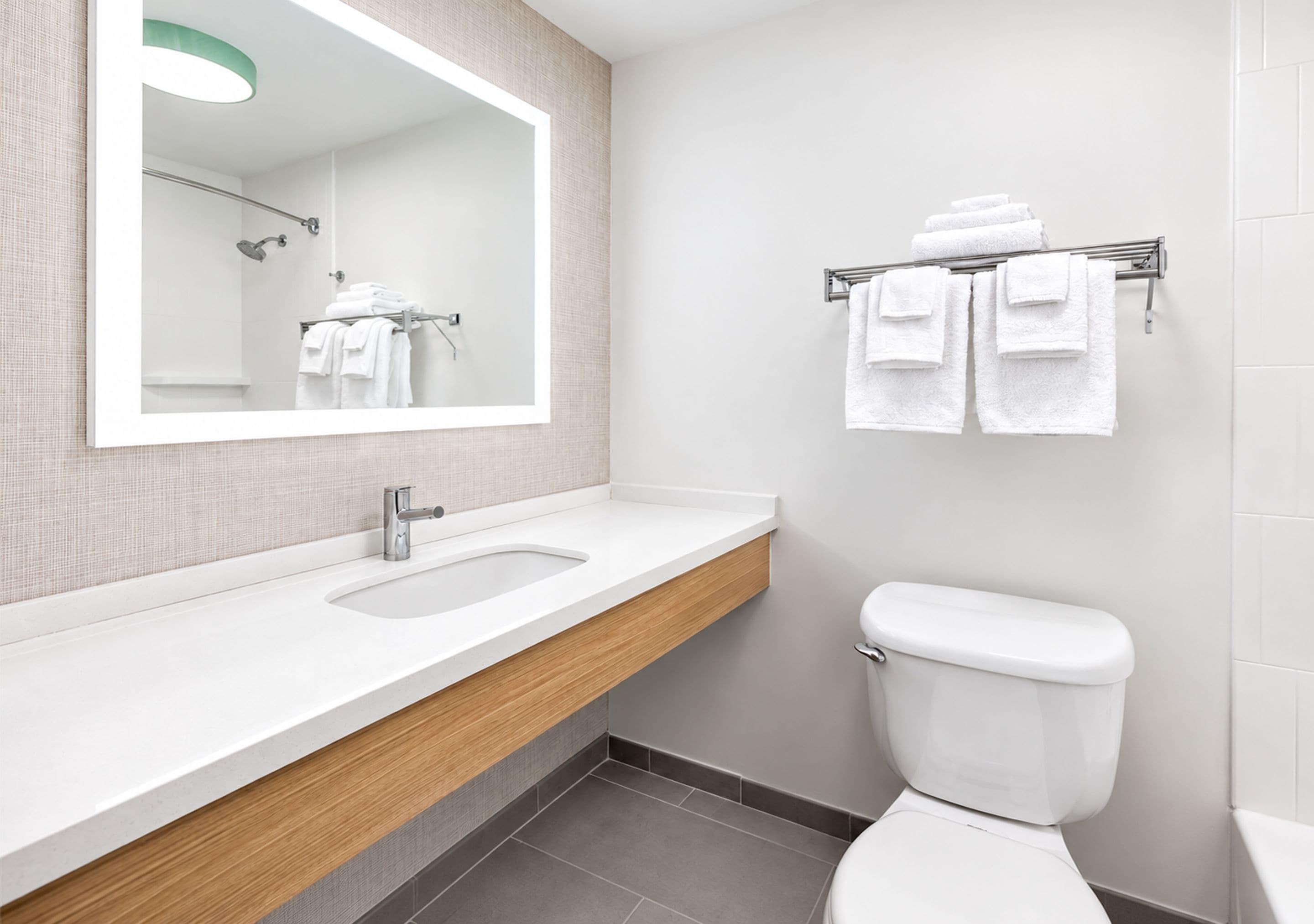 A modern bathroom with a double sink vanity, a toilet, and a towel rack.