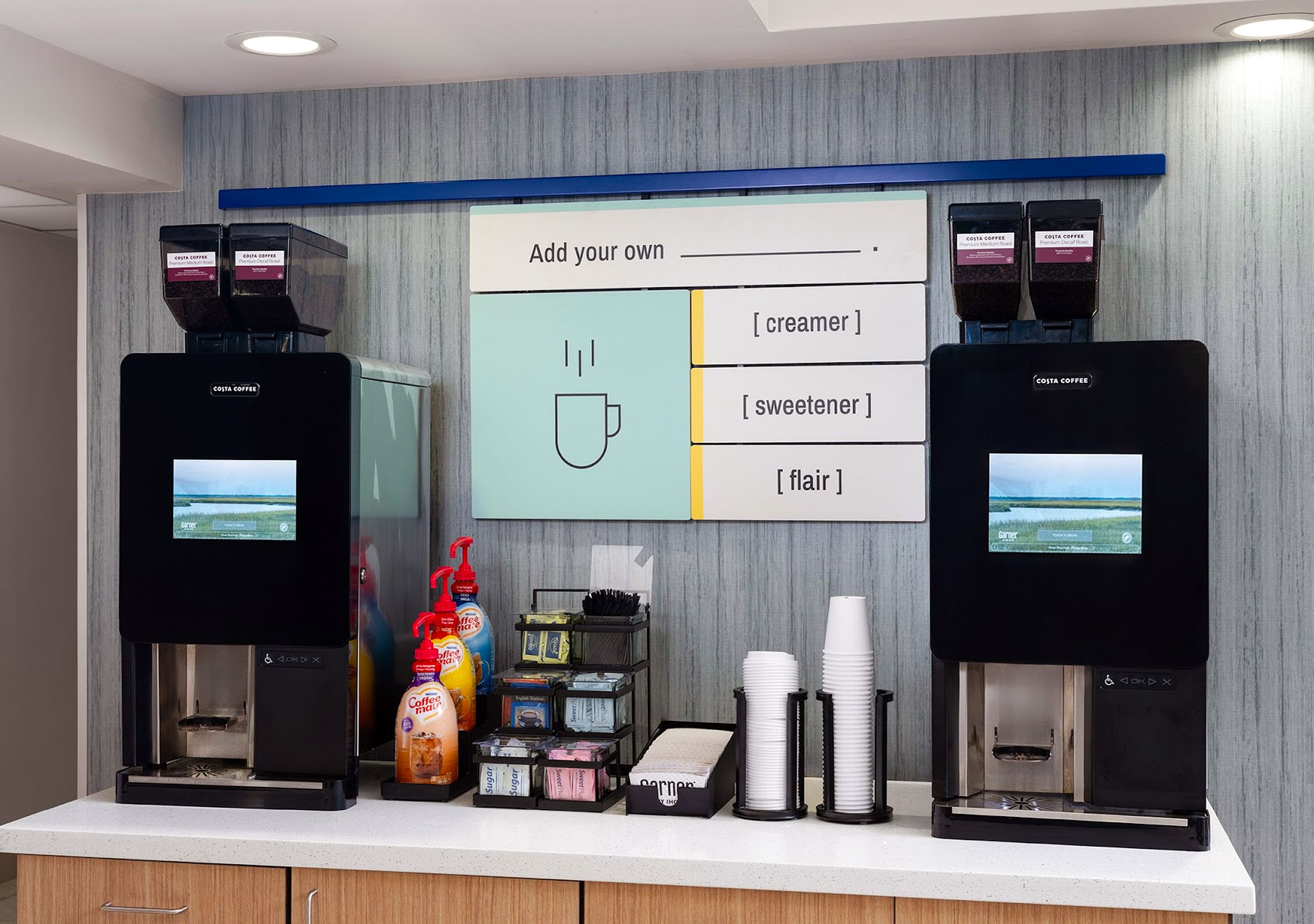 A coffee station with two coffee machines, a menu board, and various coffee-related items.