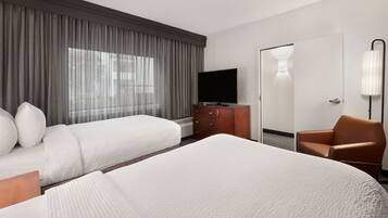 Habitación de hotel con dos camas, televisor, cómoda, silla y puerta.