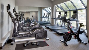 Un gimnasio con cintas de correr, elípticas y una bicicleta estática.