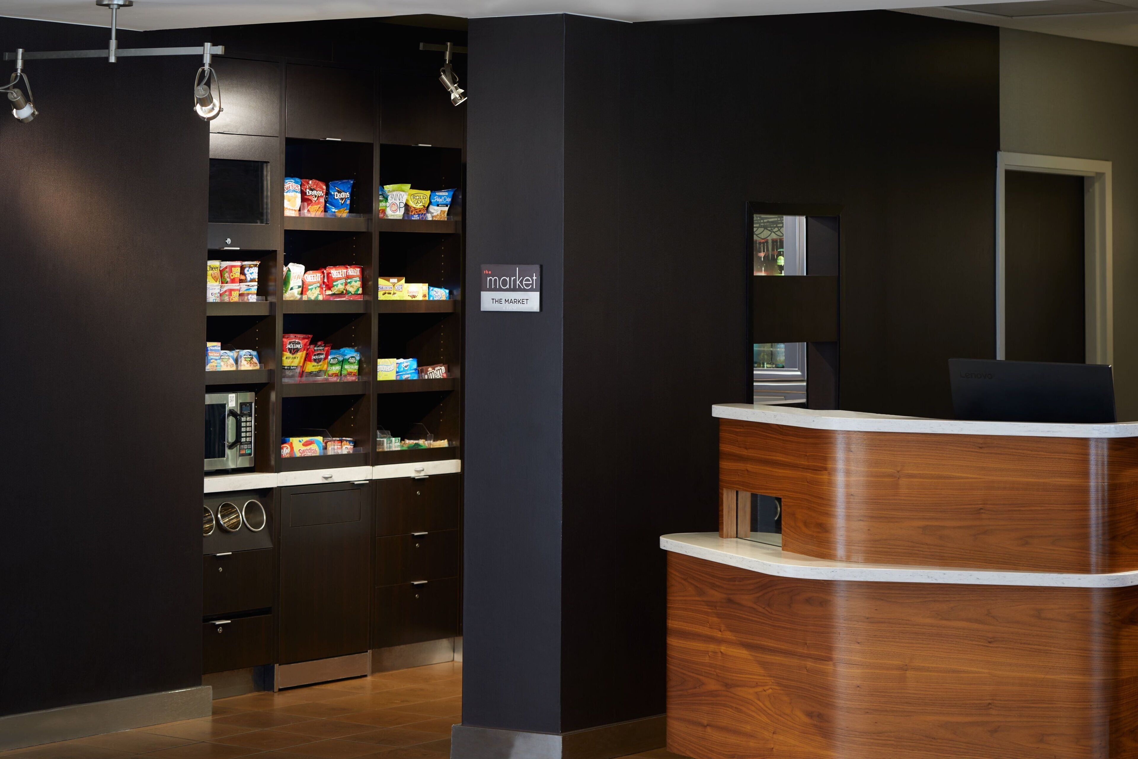 A reception area with a wooden reception desk, a microwave, and shelves stocked with snacks.
