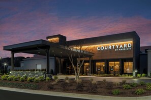 A Courtyard by Marriott hotel with a covered entrance, landscaped garden, and a modern architectural design. - Courtyard by Marriott Memphis Airport (Memphis)