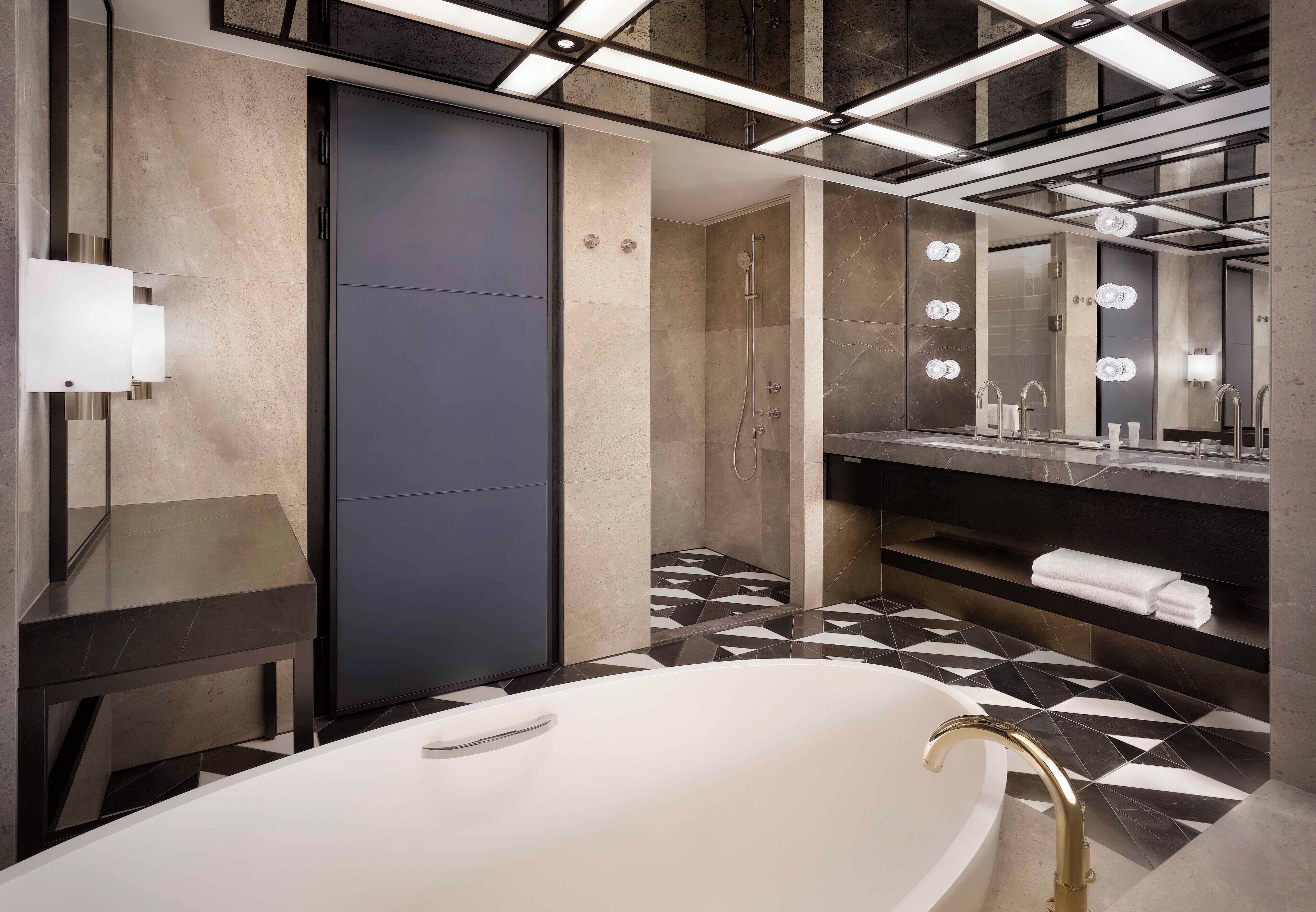 Un baño moderno con una bañera independiente, un espejo grande y un tocador con perchero.