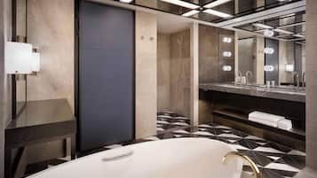 Un baño moderno con una bañera independiente, un espejo grande y un tocador con perchero.