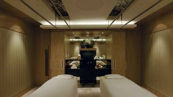 A modern spa room with wooden paneling, a central massage table, and a large mirror.