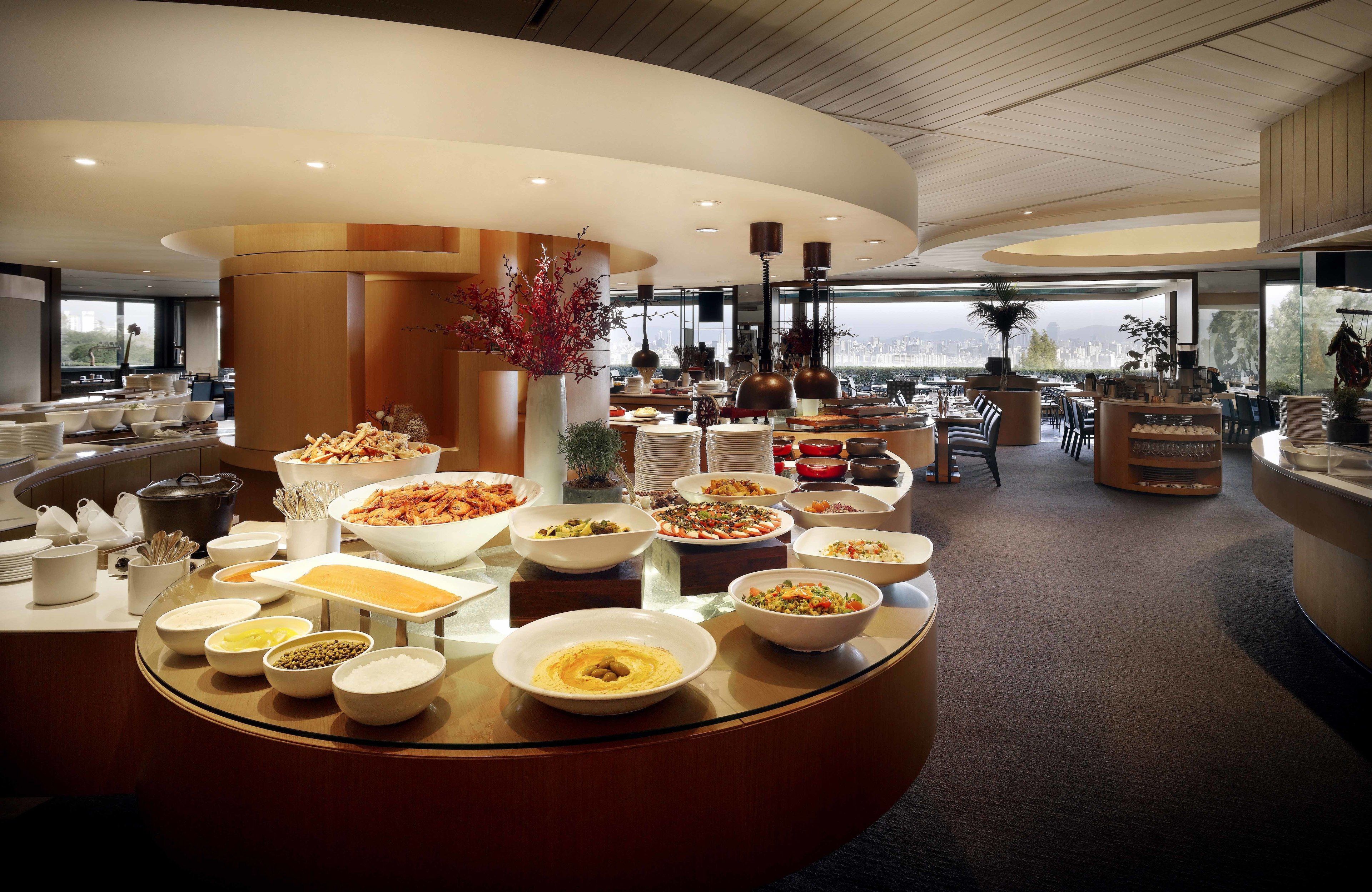 A buffet area with various dishes and a city view.