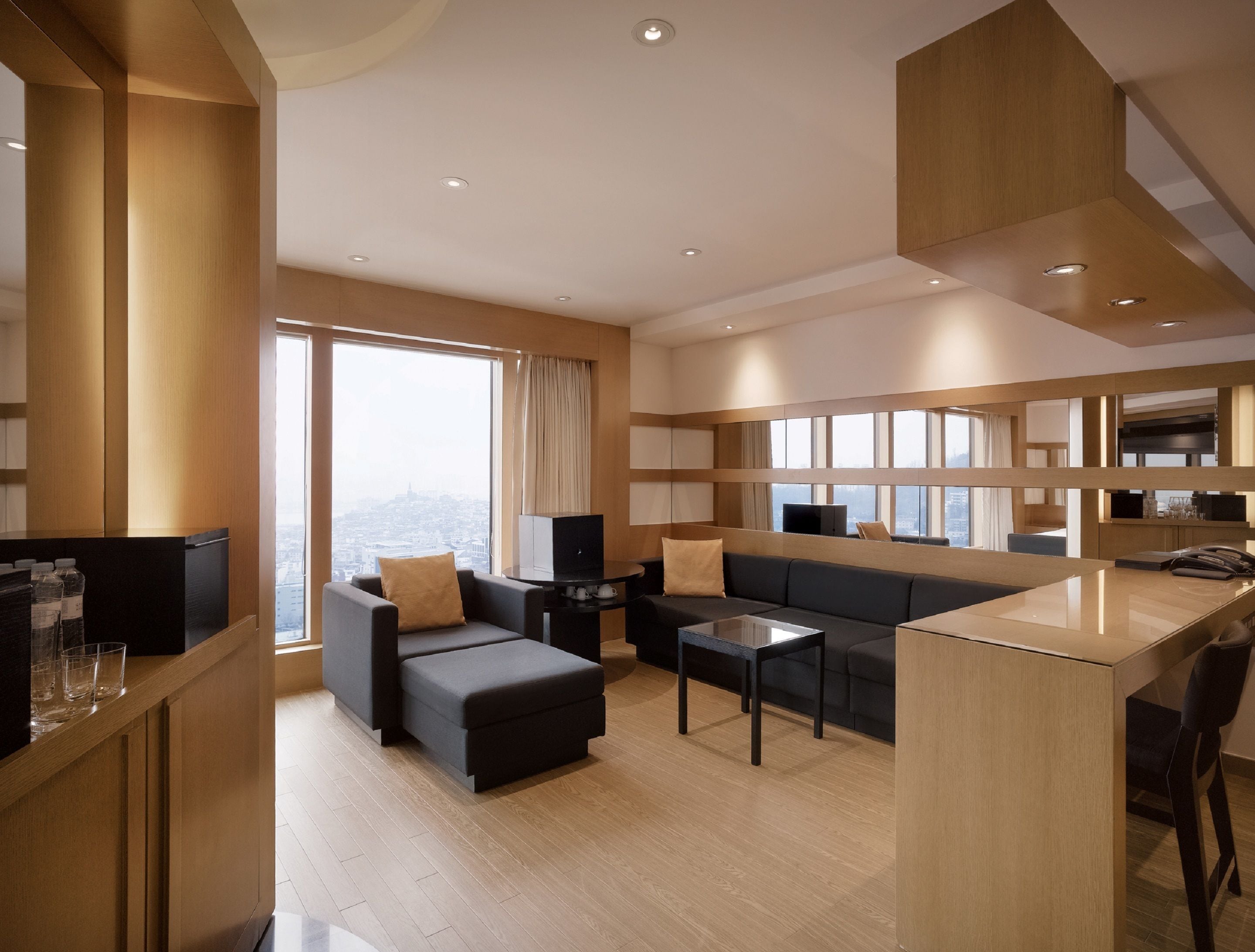 Une chambre d’hôtel moderne dotée d’une grande fenêtre, d’un canapé, d’une table basse et d’un petit coin cuisine.
