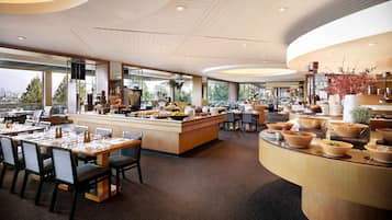 A modern hotel lobby with a central island, seating area, and large windows offering a city view.