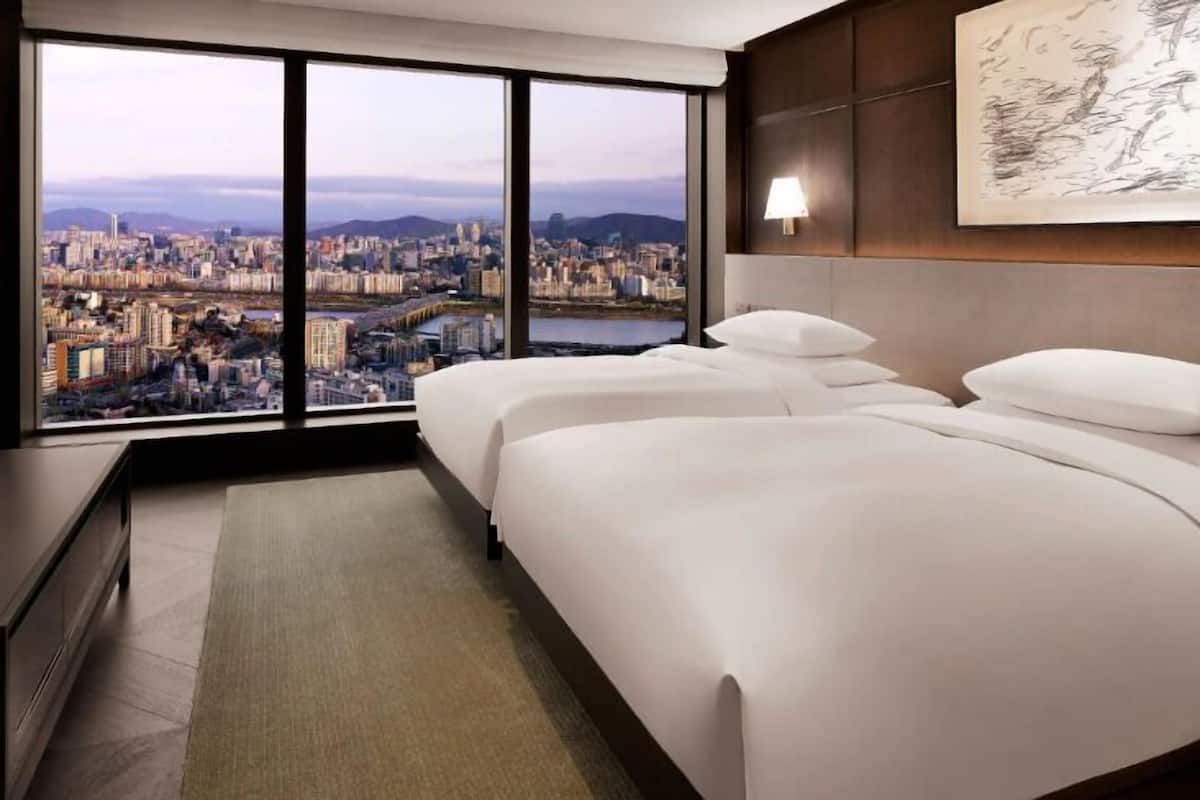 A modern hotel room with a large window offering a cityscape view.