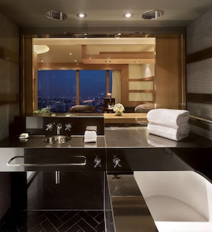 A modern bathroom with a black countertop, a sink, and a white bathtub.