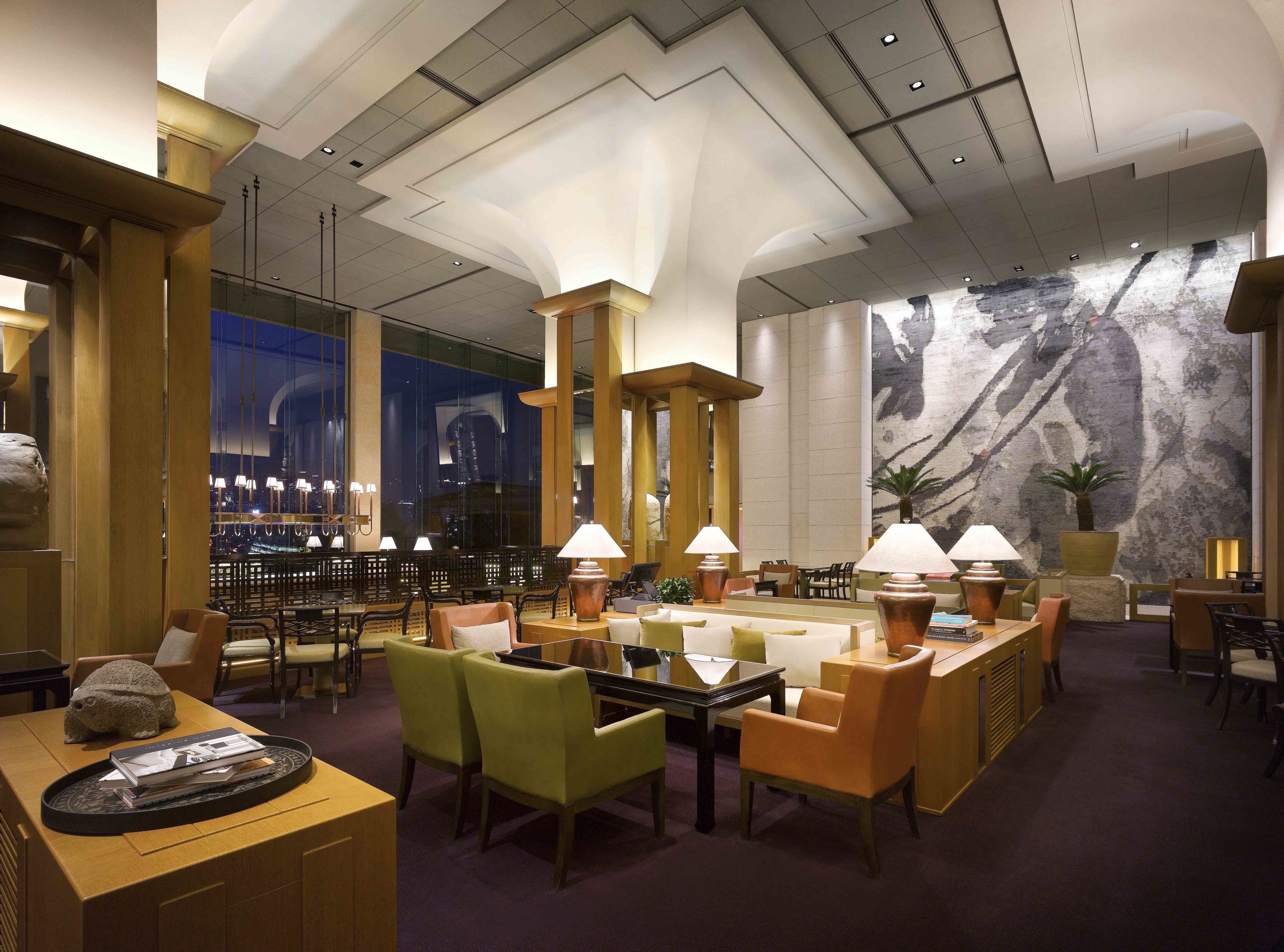A spacious lobby with high ceilings, modern lighting, and a large mural on the wall.