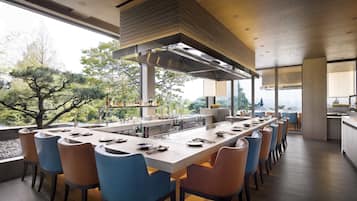 A modern kitchen with a long island, bar seating, and a view of trees.