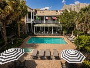 A hotel with a swimming pool, outdoor seating, and flags. - Maison St Charles (New Orleans)