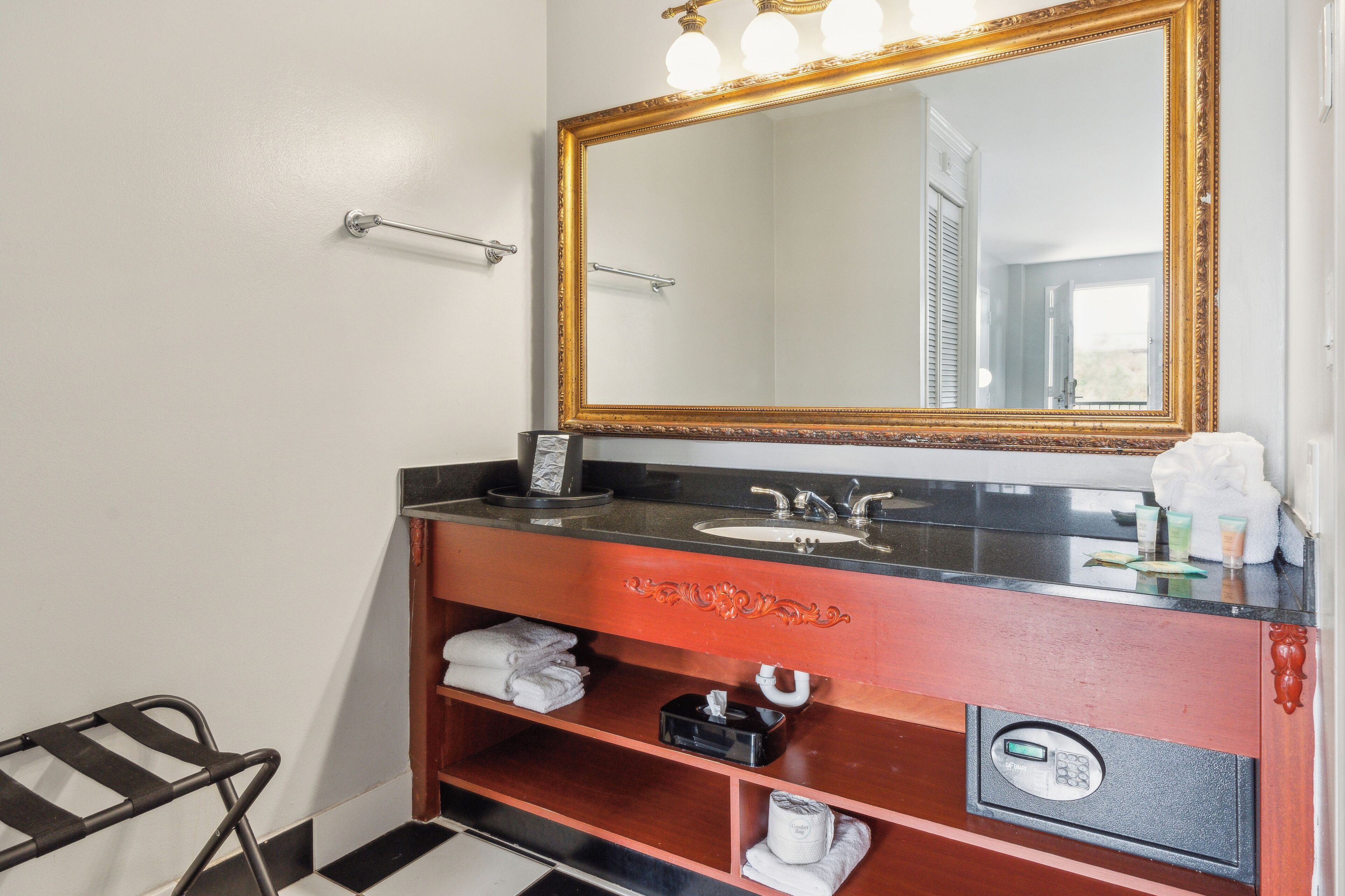A bathroom with a large mirror, a sink, and a towel rack.