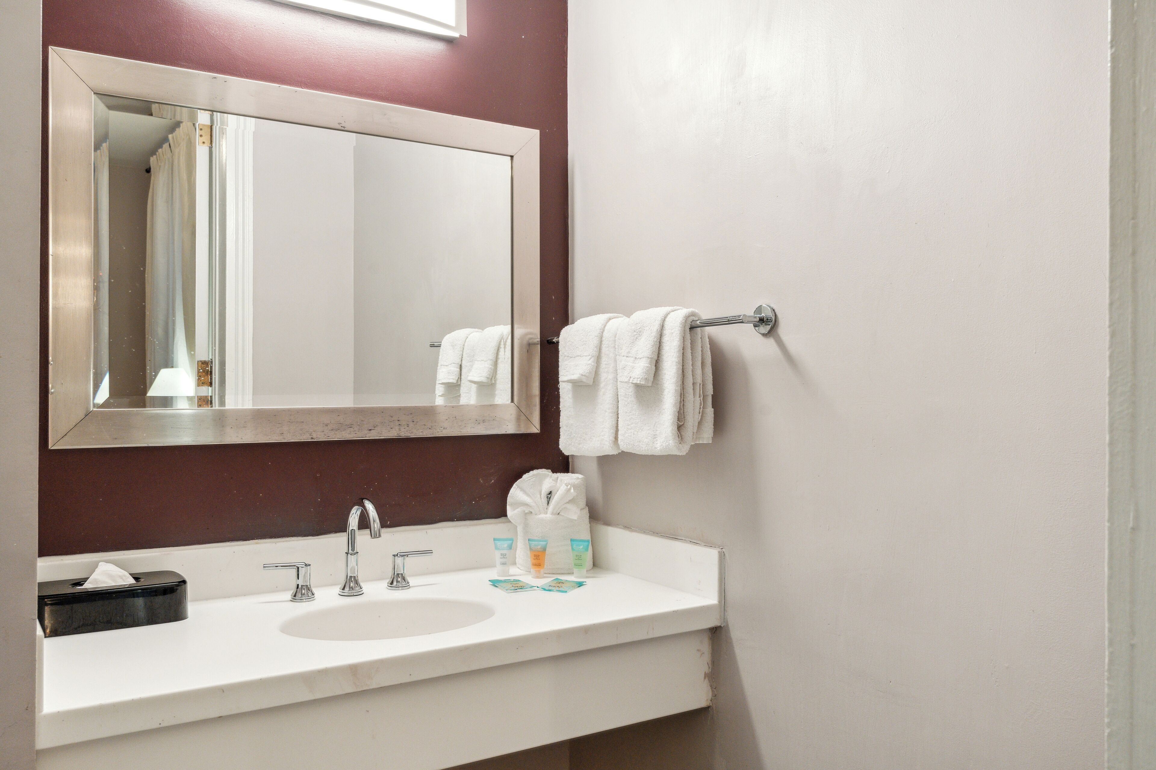 Un baño con lavamanos blanco, espejo y barra para toallas.
