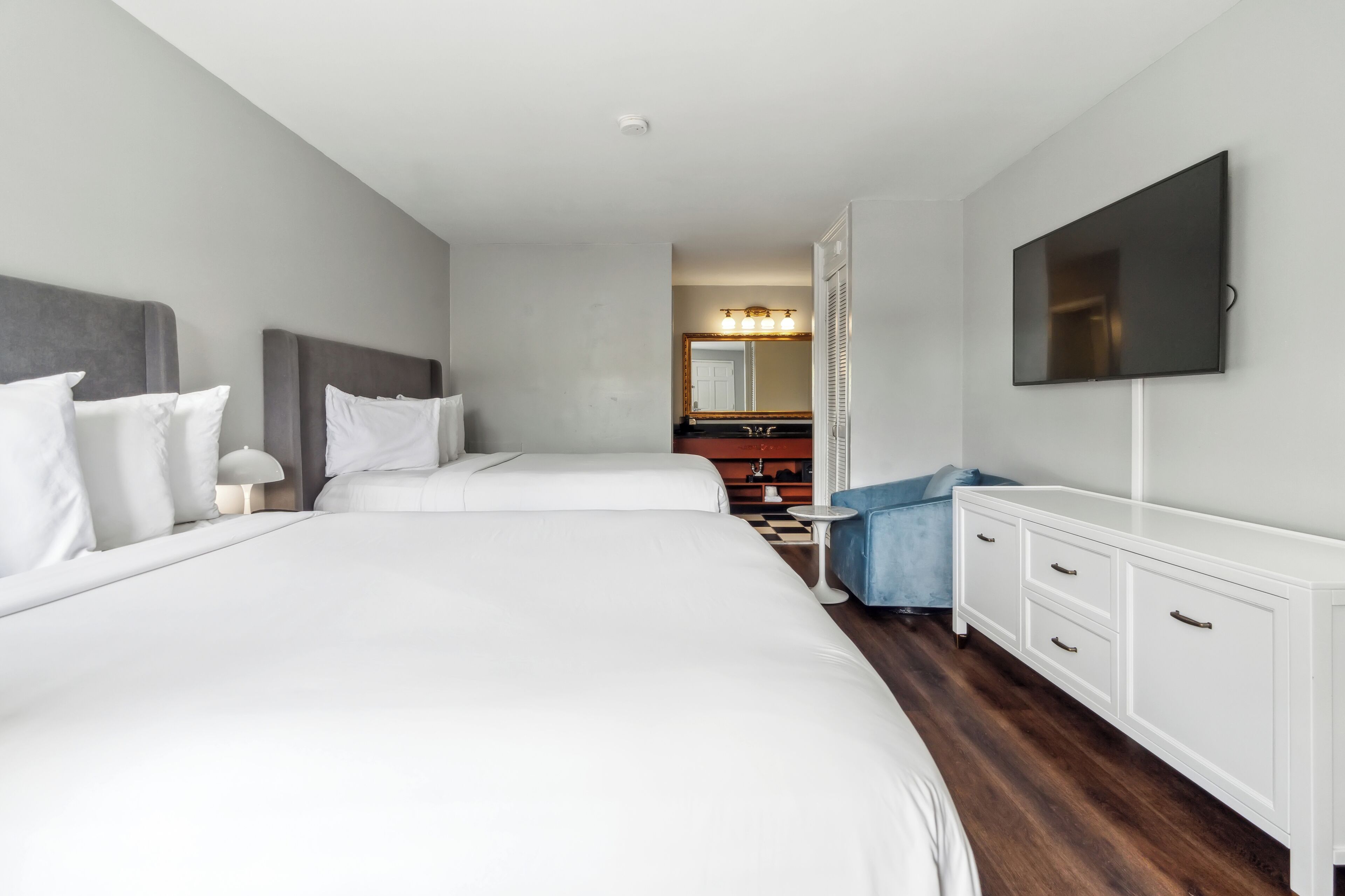 A hotel room with two beds, a TV, a dresser, and a mirror.
